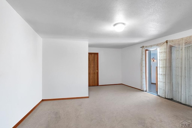 carpeted spare room with a textured ceiling and baseboards