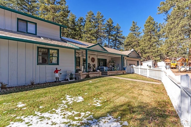 traditional-style house with a garage, board and batten siding, a front yard, and a fenced backyard