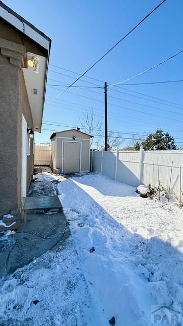 1326 E River St, Pueblo, CO 81001 - yard layered in snow featuring an outbuilding, a fenced backyard, and a storage unit
