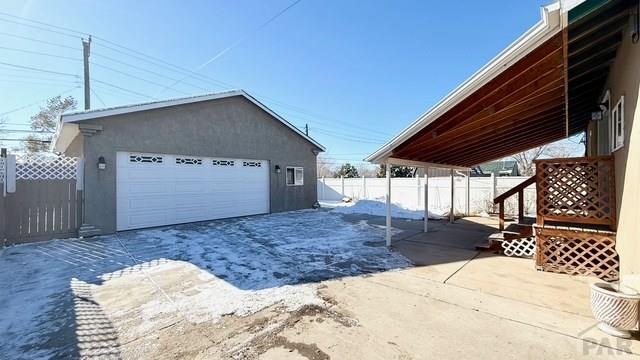 1326 E River St, Pueblo, CO 81001 - view of home's exterior featuring stucco siding, an outdoor structure, fence, and a detached garage