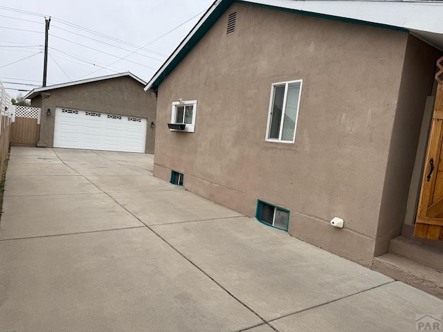 1326 E River St, Pueblo, CO 81001 - view of side of property featuring an outdoor structure, a detached garage, stucco siding, and fence