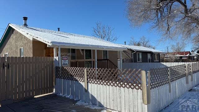 1326 E River St, Pueblo, CO 81001 - view of front of house with a porch, stucco siding, and a fenced front yard