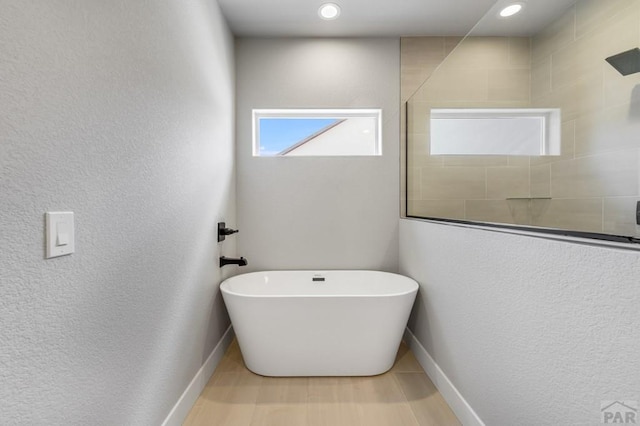 bathroom with recessed lighting, wood finished floors, a freestanding tub, baseboards, and a walk in shower