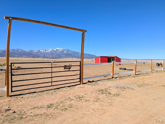 view of yard featuring an outdoor structure, fence, a rural view, and a mountain view