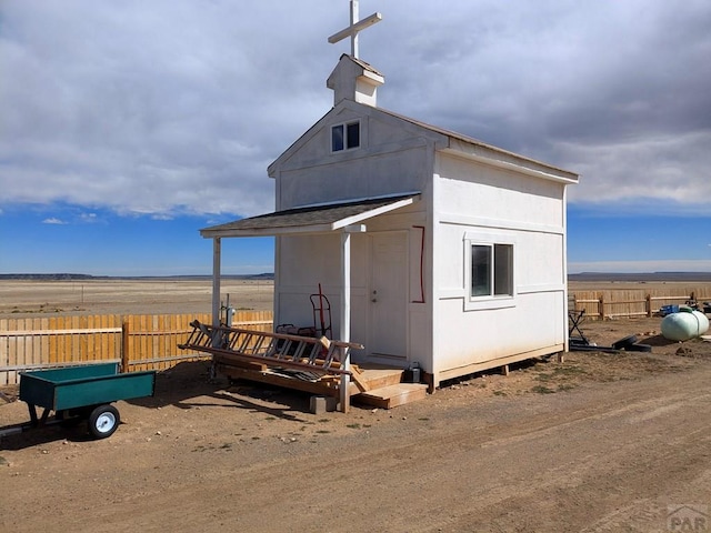 view of outdoor structure with a rural view, an outdoor structure, and fence