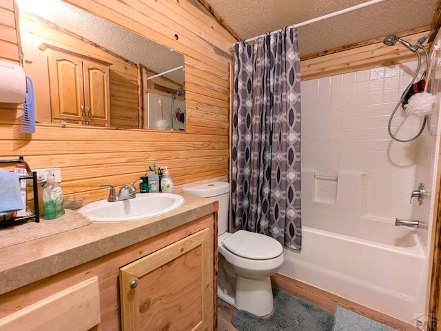 full bathroom featuring vanity, wooden walls, shower / bath combo with shower curtain, a textured ceiling, and toilet