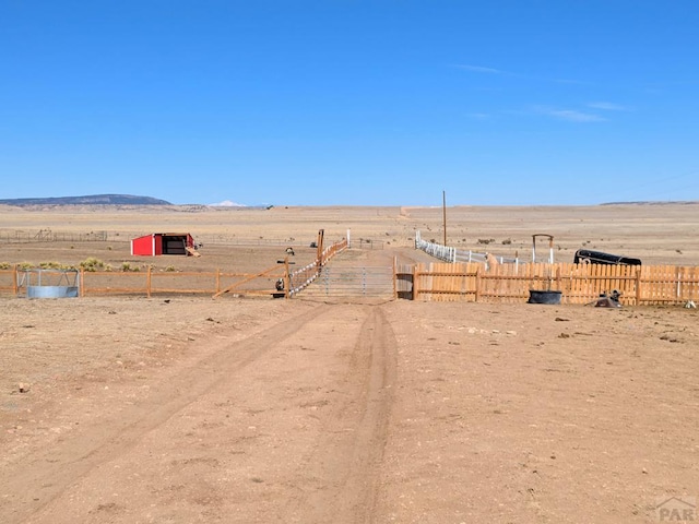 view of yard with a rural view, fence, and a mountain view