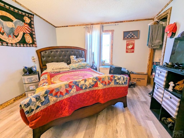 bedroom with a textured ceiling, crown molding, and wood finished floors