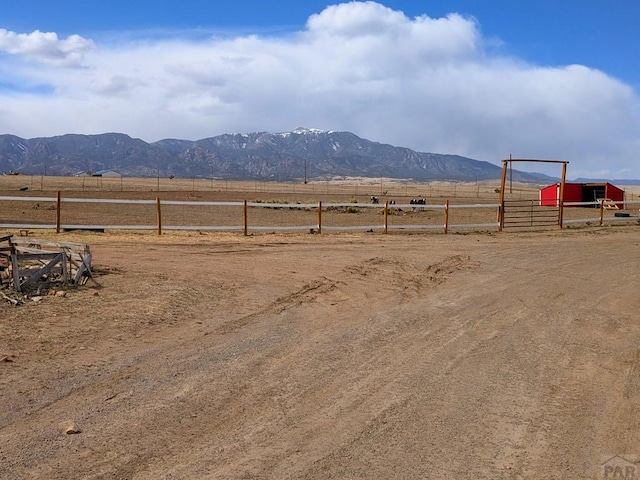 view of yard with a mountain view, a rural view, an outdoor structure, and fence