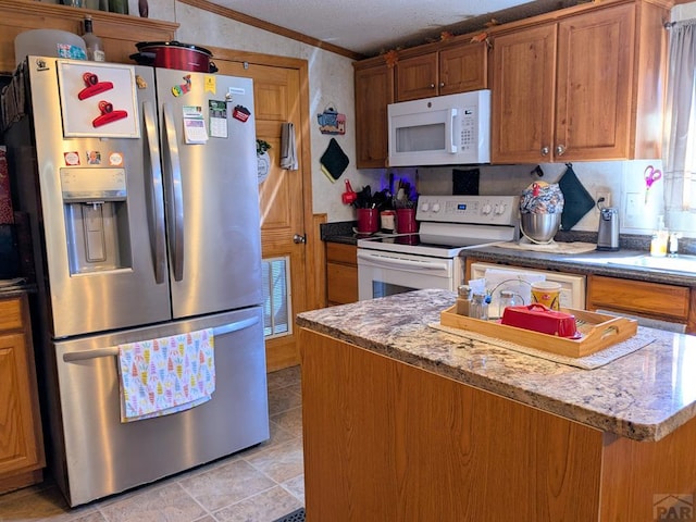 kitchen with a kitchen island, light stone countertops, ornamental molding, brown cabinetry, and white appliances