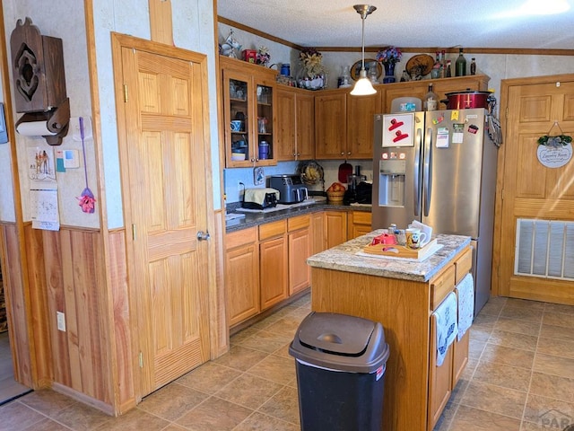 kitchen with visible vents, a textured ceiling, stainless steel fridge with ice dispenser, crown molding, and glass insert cabinets