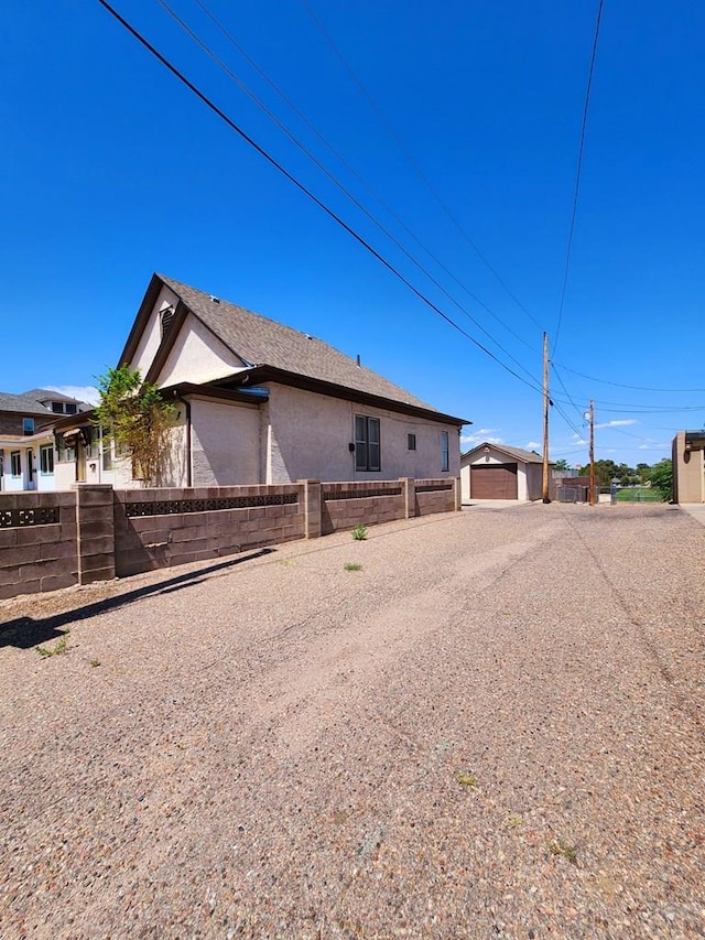 view of property exterior with fence private yard, an outbuilding, and stucco siding