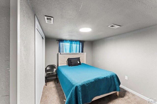 bedroom with a textured ceiling, carpet floors, and visible vents