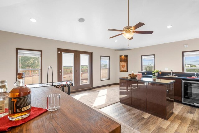 kitchen featuring light wood finished floors, beverage cooler, dark countertops, a kitchen island, and modern cabinets