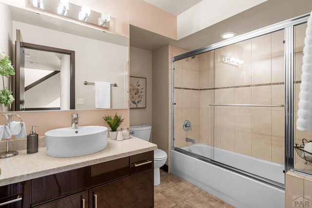 full bathroom featuring bath / shower combo with glass door, vanity, toilet, and tile patterned floors