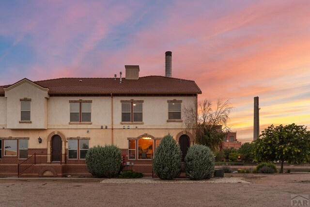 view of front of property with a chimney, a tile roof, and stucco siding