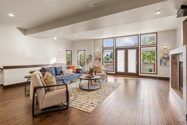 living area featuring dark wood-style floors, baseboards, a fireplace, and visible vents