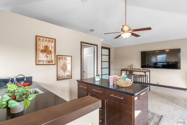 kitchen featuring dark countertops, a ceiling fan, open floor plan, vaulted ceiling, and dark brown cabinetry