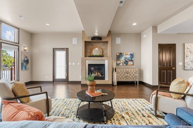 living room featuring dark wood-style floors, a fireplace, and a healthy amount of sunlight