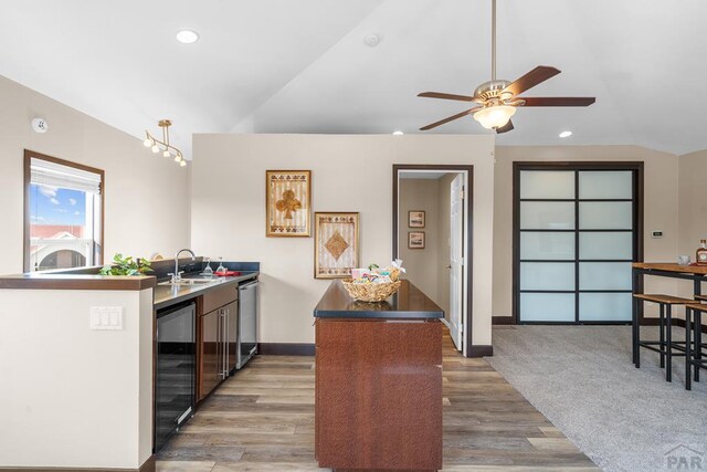 kitchen featuring wine cooler, recessed lighting, wood finished floors, a sink, and vaulted ceiling