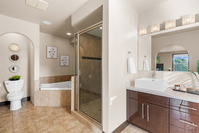 full bathroom featuring a stall shower, a garden tub, vanity, and toilet