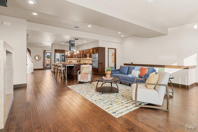 living room with baseboards, visible vents, dark wood-type flooring, and recessed lighting