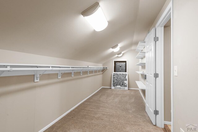 spacious closet featuring vaulted ceiling and light colored carpet