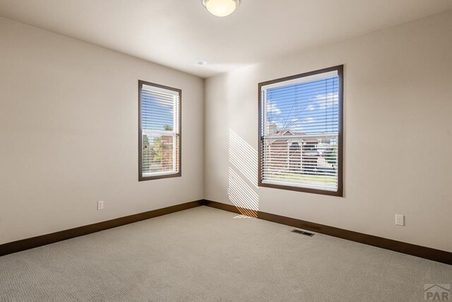 empty room featuring carpet floors, visible vents, and baseboards