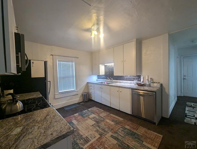 kitchen with stainless steel appliances, a sink, white cabinetry, baseboards, and decorative backsplash