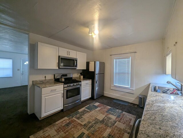 kitchen featuring baseboards, white cabinets, appliances with stainless steel finishes, light countertops, and a sink