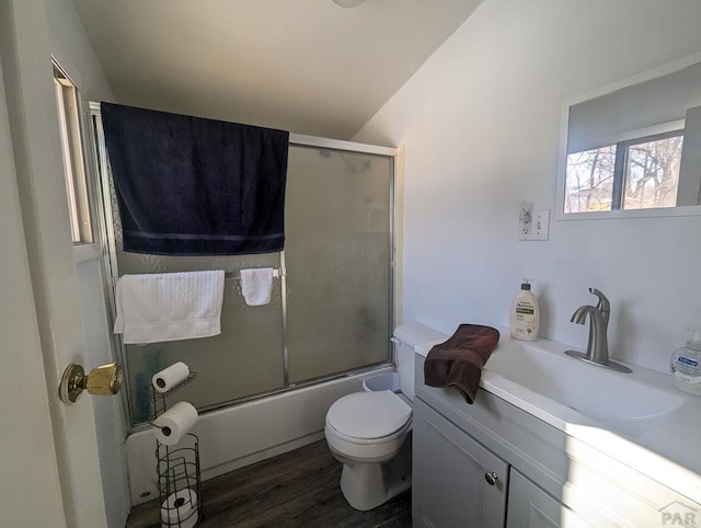 full bath featuring vanity, combined bath / shower with glass door, wood finished floors, and toilet