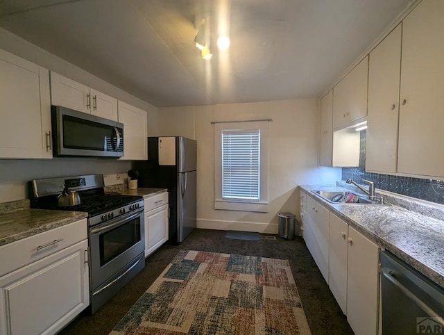 kitchen with baseboards, stainless steel appliances, a sink, and white cabinets