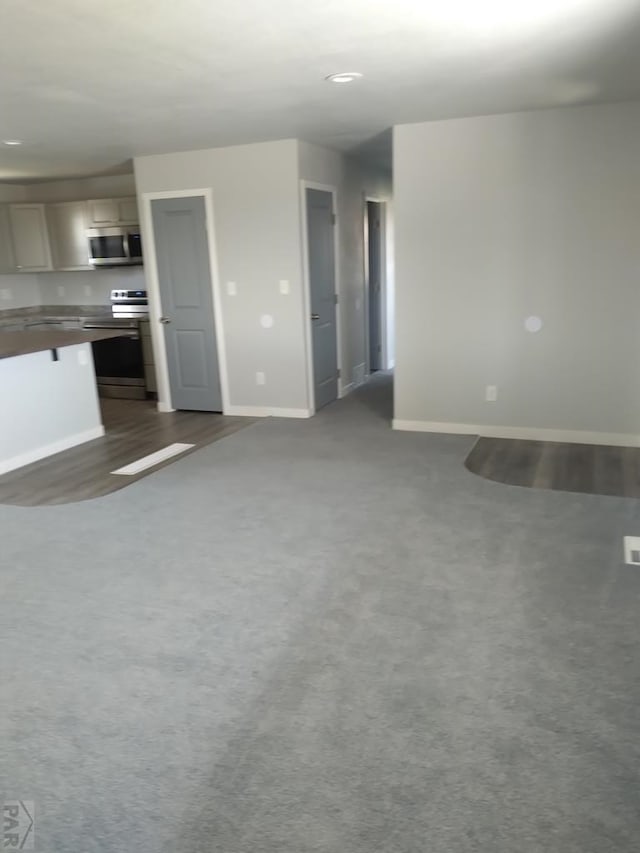1708 W 8th St, Las Animas, CO 81054 - unfurnished living room with dark wood-style floors and dark colored carpet
