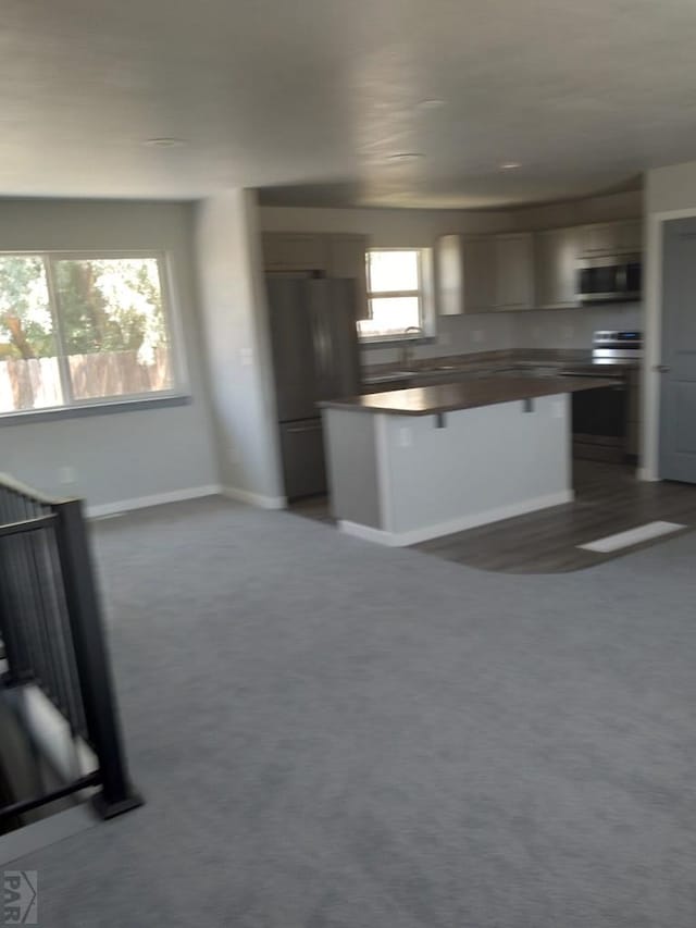 1708 W 8th St, Las Animas, CO 81054 - kitchen with appliances with stainless steel finishes, carpet flooring, a breakfast bar, butcher block countertops, and a center island
