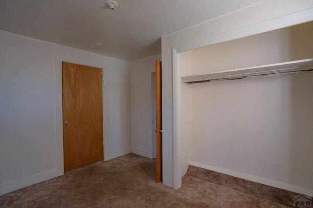 unfurnished bedroom featuring baseboards, a closet, and carpet flooring