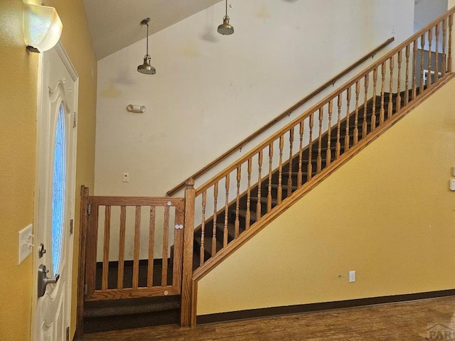 stairs featuring high vaulted ceiling, baseboards, and wood finished floors