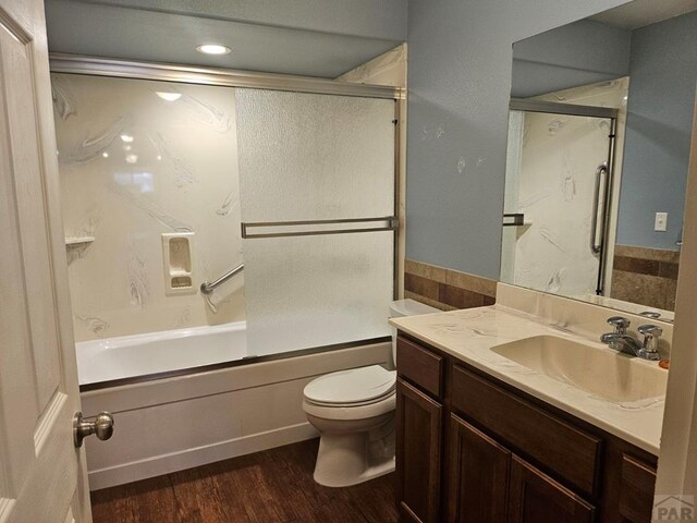 full bathroom featuring enclosed tub / shower combo, toilet, wood finished floors, and vanity