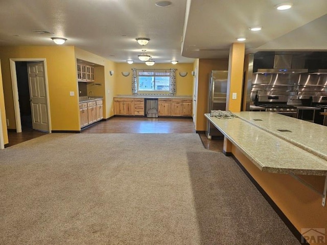 kitchen featuring light stone counters, appliances with stainless steel finishes, dark colored carpet, and a breakfast bar area