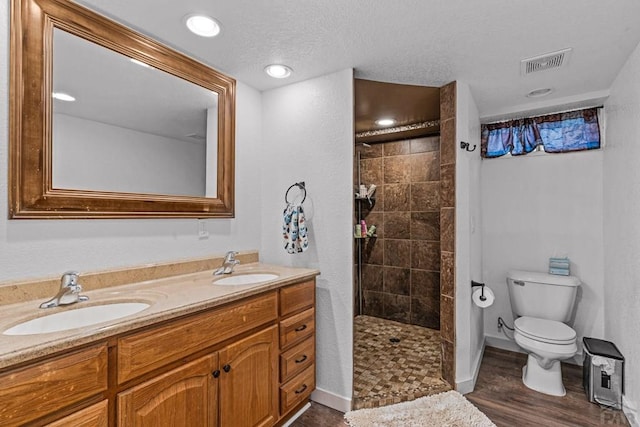 36 Loyola Ln, Pueblo, CO 81005 - bathroom featuring double vanity, toilet, tiled shower, wood finished floors, and baseboards