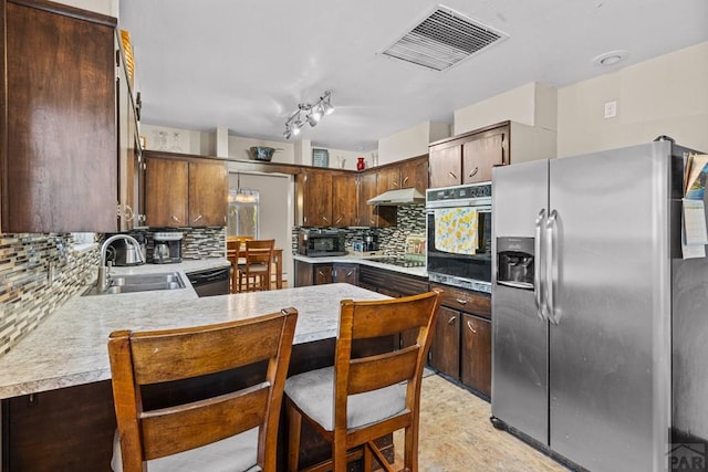 36 Loyola Ln, Pueblo, CO 81005 - kitchen featuring stainless steel appliances, a sink, under cabinet range hood, backsplash, and a peninsula