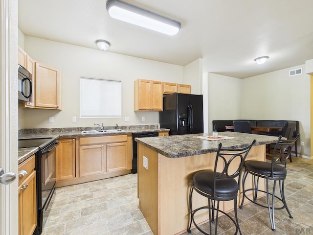 kitchen with a breakfast bar area, visible vents, a sink, black appliances, and a center island