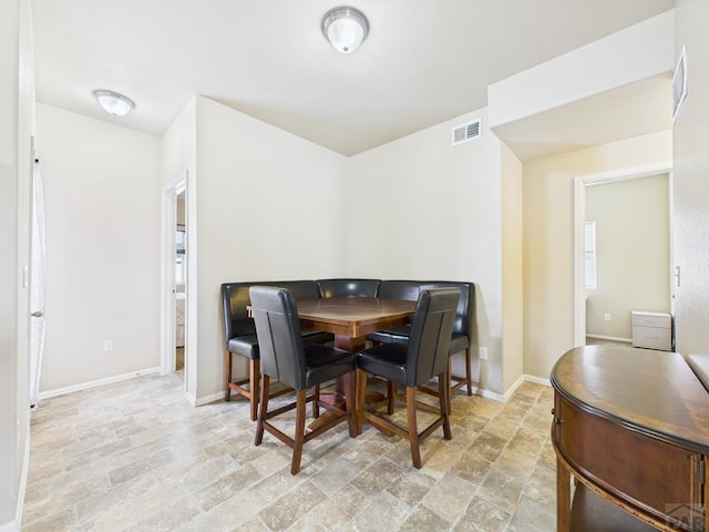 dining space featuring visible vents, baseboards, and stone finish floor