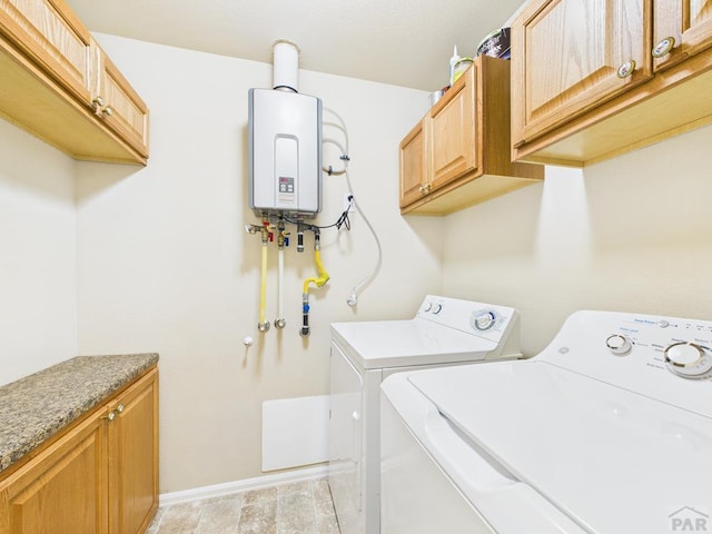 laundry area featuring independent washer and dryer, cabinet space, water heater, and baseboards