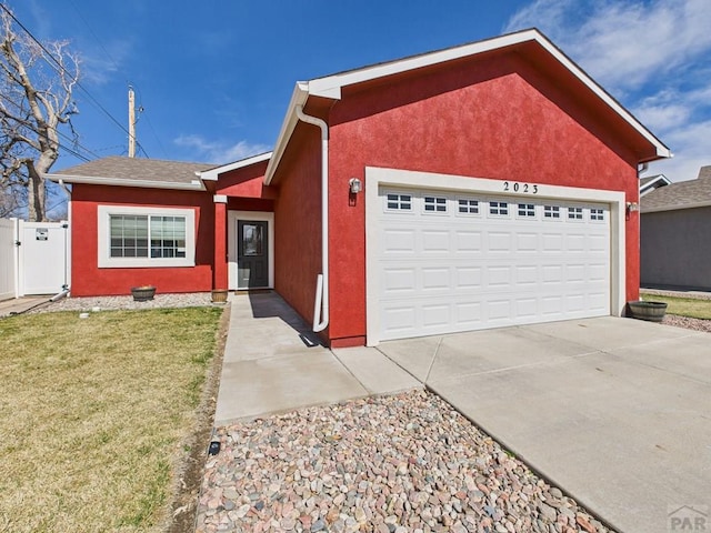 ranch-style house with an attached garage, a front lawn, stucco siding, driveway, and a gate