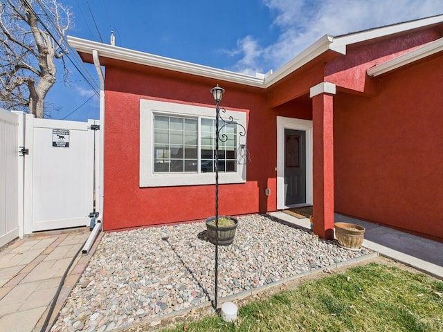 property entrance with stucco siding and a gate