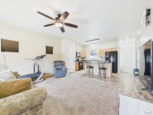 living room featuring baseboards, light wood-style floors, and ceiling fan