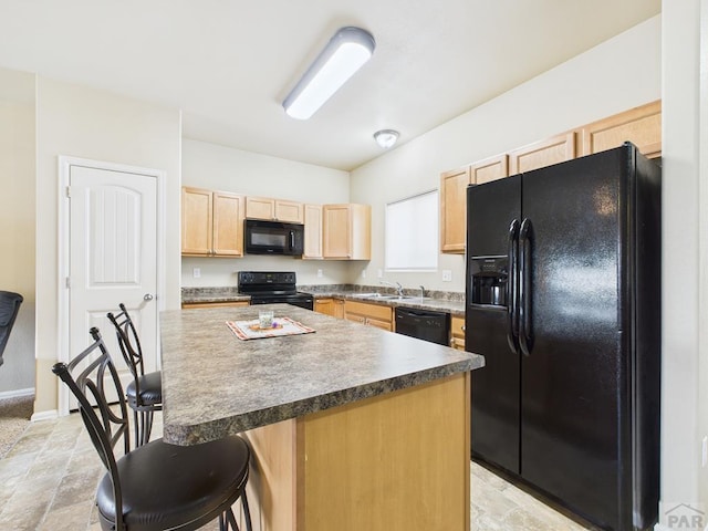 kitchen featuring a kitchen island, light brown cabinetry, a kitchen bar, black appliances, and a sink