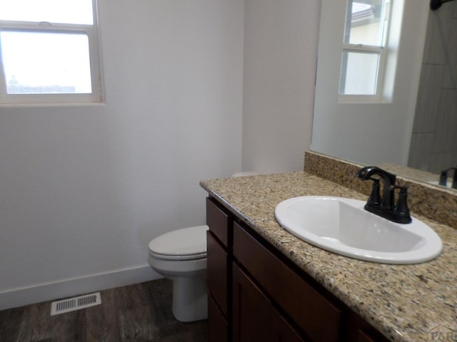 bathroom with visible vents, toilet, a healthy amount of sunlight, and wood finished floors