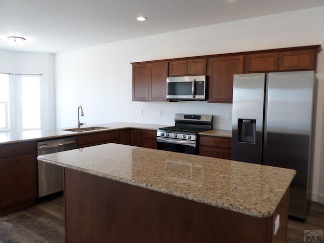 kitchen featuring a sink, recessed lighting, stainless steel appliances, light stone countertops, and dark wood-style flooring