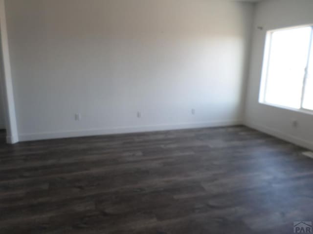 unfurnished room with baseboards and dark wood-style flooring